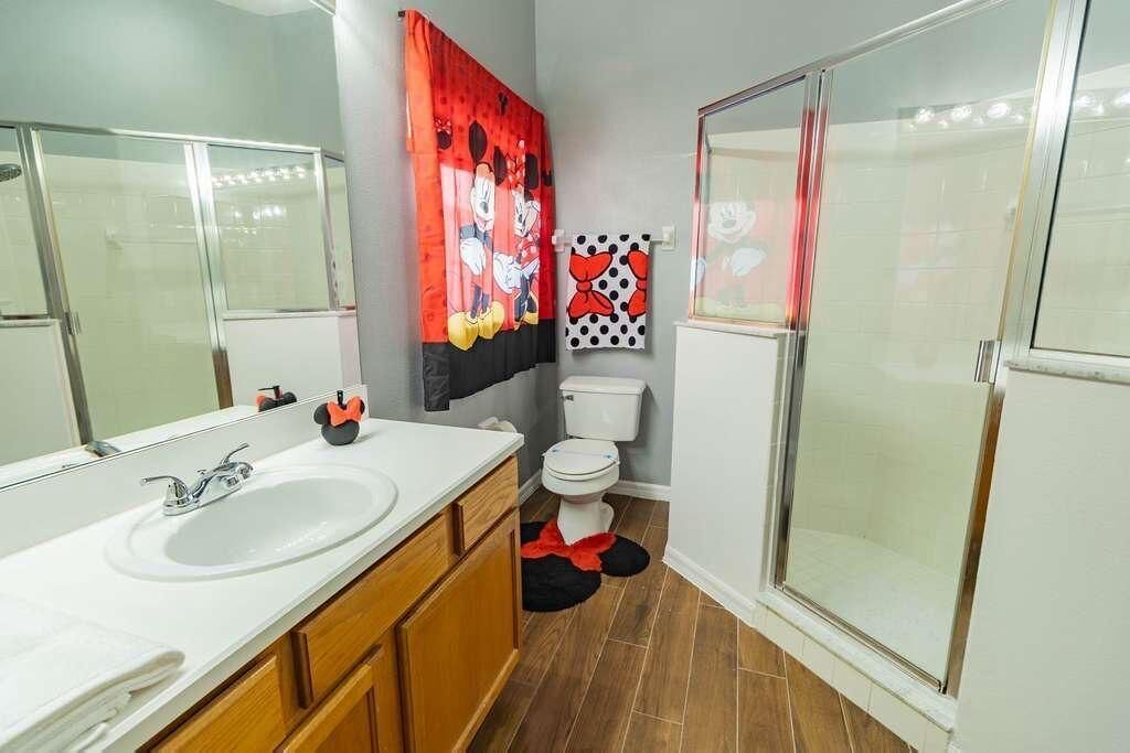 A bathroom with a double sink, toilet, and glass shower enclosure.