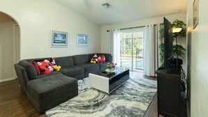 Ein Wohnzimmer mit einer Eckcouch, einem Couchtisch und einem Fernseher.