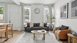 Un salon avec un canapé, une table basse et une horloge au mur.