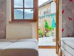 Ein Zimmer mit zwei Betten, einem Fenster mit Bergblick, einer Holztür, die nach draußen führt, und einem Schild, das auf einen Garten hinweist.