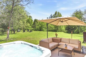 Ein Whirlpool, Gartenmöbel und ein Sonnenschirm im Hinterhof.