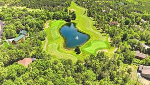 Ilmakuva golfkentästä, jossa on lampi, ja jonka ympärillä on tiheää metsää sekä asuinalueita.