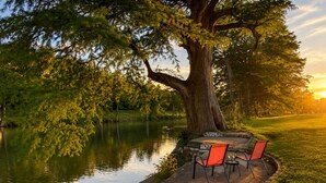 Un espace extérieur paisible, aménagé avec une table et des chaises, situé au bord d’un lac et entouré d’arbres.