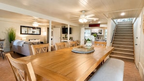 Un grand espace à manger avec une table en bois, des bancs et un ventilateur de plafond.