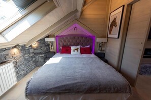 A bedroom with a sloped ceiling, stone wall, and a bed with a headboard. - Palazzo Di Acqua  (Le Mans)