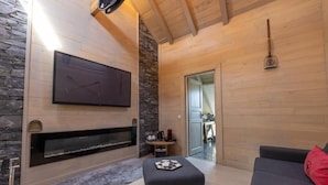 A modern living room with a fireplace, a flat-screen TV, and a cozy seating area. - Palazzo Di Acqua  (Le Mans)
