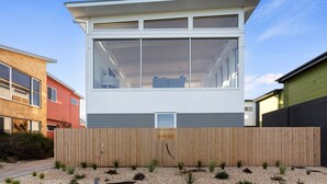 A modern two-story house with large windows, a wooden fence, and a gravel garden. - Cedar Tides - Hot Tub & Waterfront (Apollo Bay)