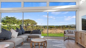 A modern living room with a large sliding glass door leading to a scenic outdoor view. - Cedar Tides - Hot Tub & Waterfront (Apollo Bay)