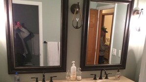 Un baño con dos lavamanos, armarios de madera y dos espejos grandes.