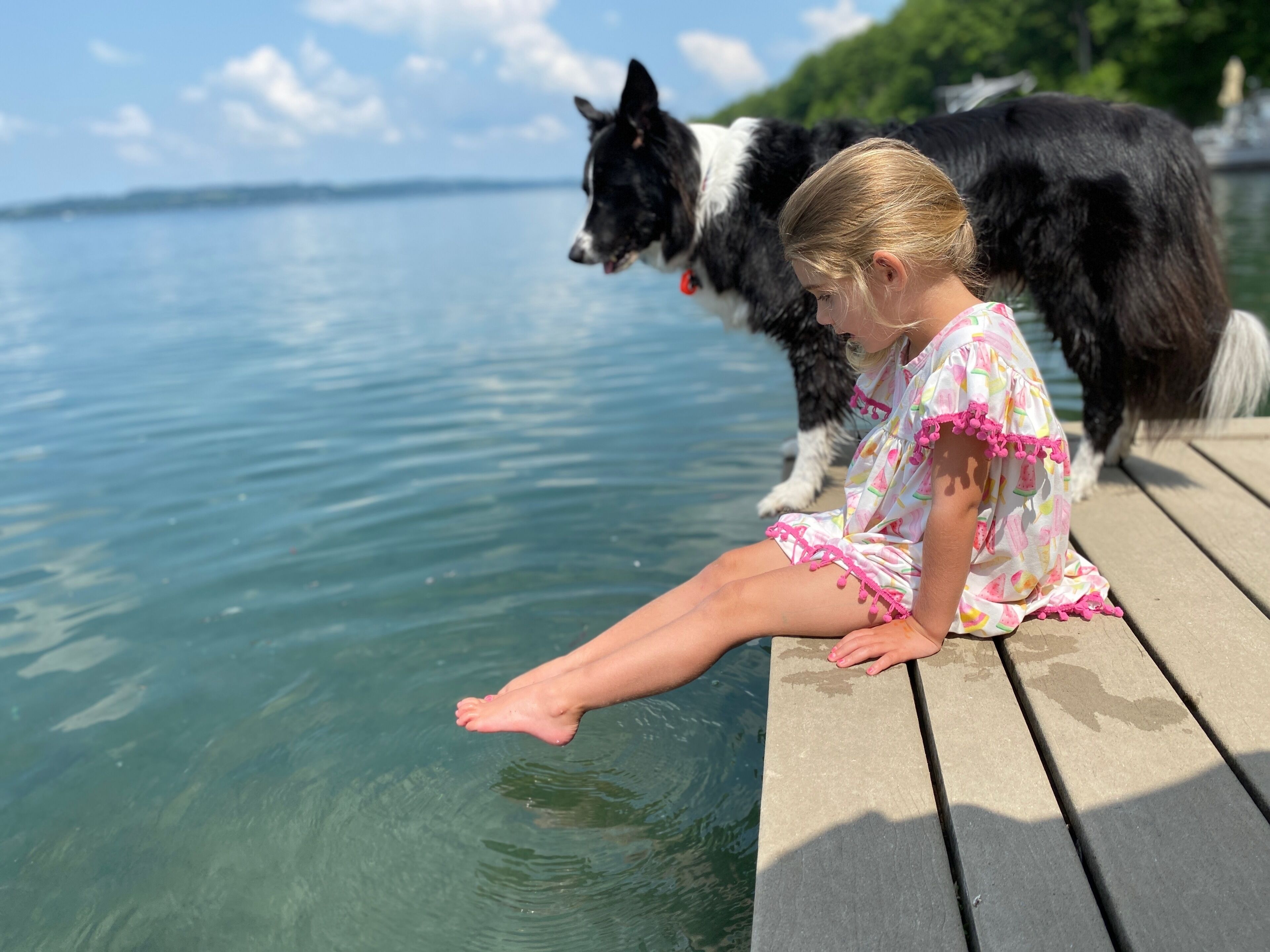 A person sitting on a wooden dock by a body of water.