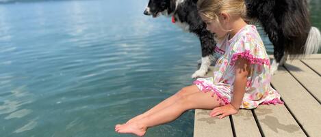 A person sitting on a wooden dock by a body of water.