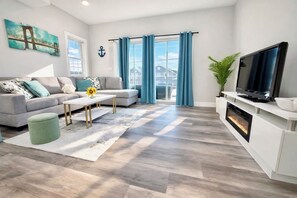 A modern living room with a sofa, coffee table, TV, and a fireplace. - Modern Beach House,  Rooftop Deck & Ocean Views, Walk to Beach & Boardwalk (Seaside Heights)