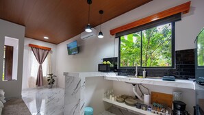 A modern kitchen with marble flooring, a window with a view of greenery, a microwave, and a coffee maker. - River Collection - Villa Tranquil #3 sounds of the river (La Fortuna)