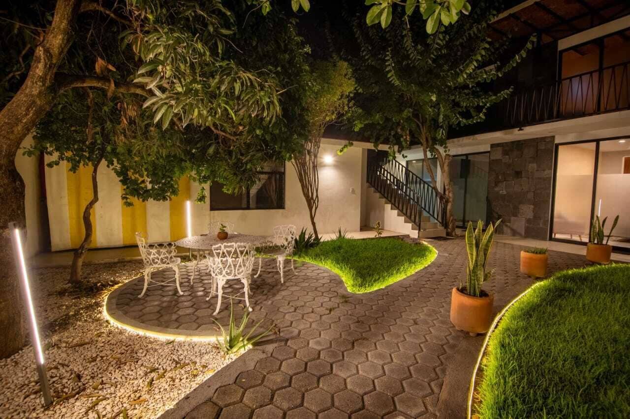 A courtyard with a dining area, potted plants, and a staircase leading to a building.