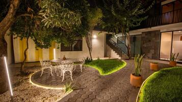 A courtyard with a dining area, potted plants, and a staircase leading to a building.