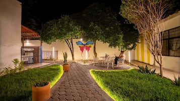 Un patio con un sendero adoquinado, plantas en macetas y un mural de mariposas en la pared.