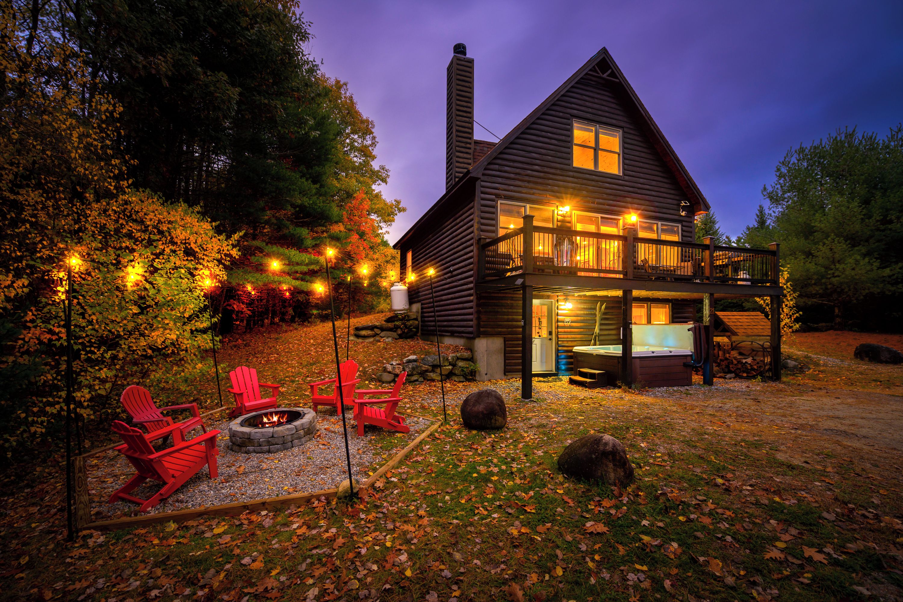 A log cabin with a deck, outdoor seating, and a fire pit.