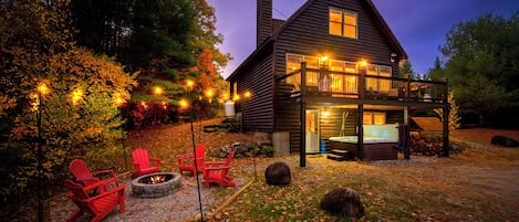 Eine Blockhütte mit einer Terrasse, Sitzgelegenheiten im Freien und einer Feuerstelle.