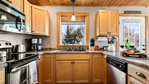 Una cocina con armarios de madera, electrodomésticos de acero inoxidable, un ventanal con vistas y un letrero que dice 'VACATIONLAND'.