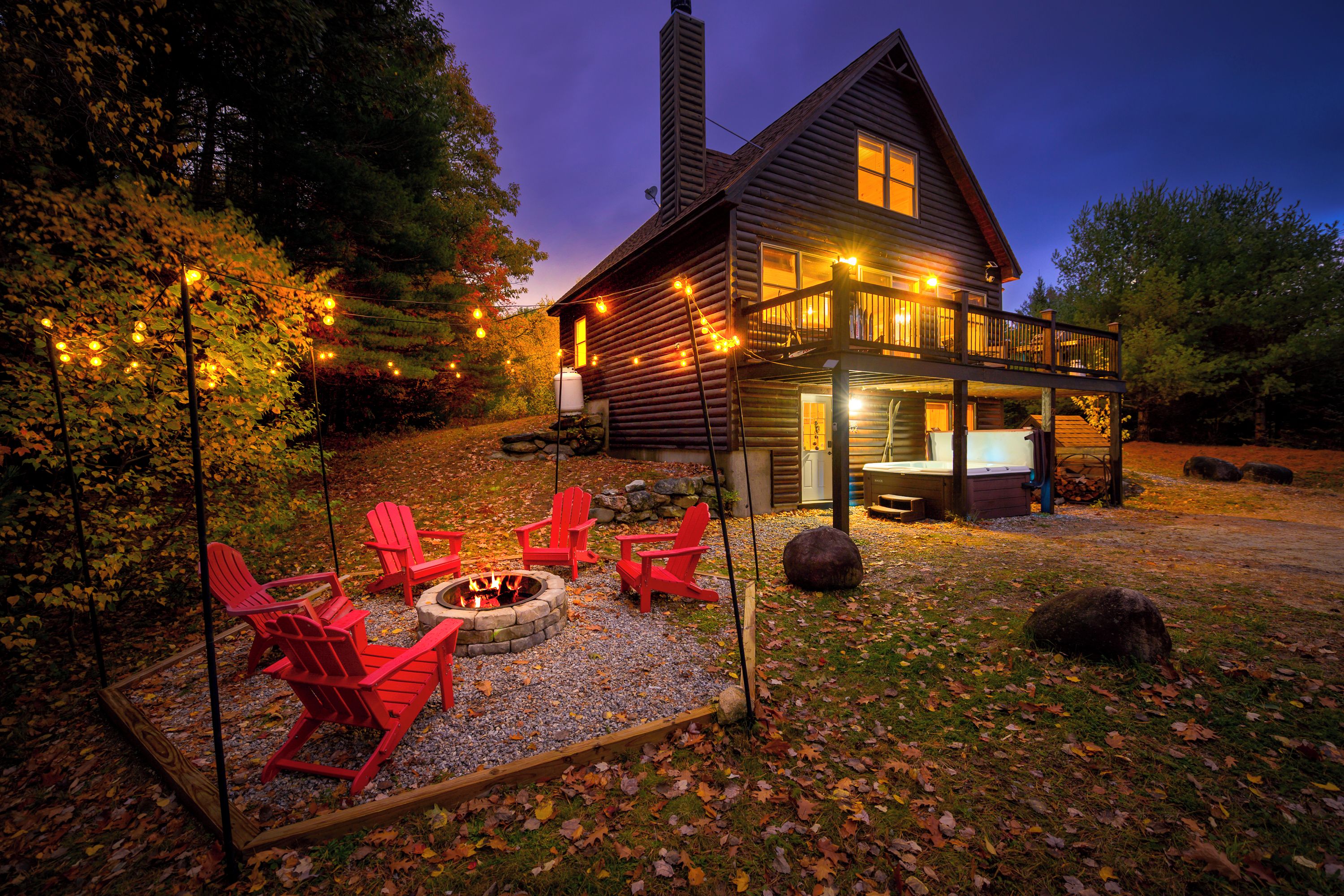 A log cabin with a deck, outdoor seating, and a fire pit.