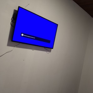 Seinälle asennettu litteänäyttöinen televisio, jonka sinisellä näytöllä näkyy viesti vieraalla kielellä.