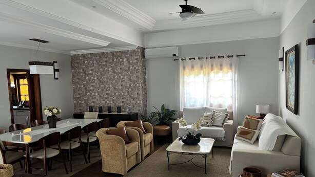 A modern living room with a dining area, a sofa set, a coffee table, and a decorative vase. - Beautiful and comfortable house with security in a gated community near São Paulo. (Atibaia)