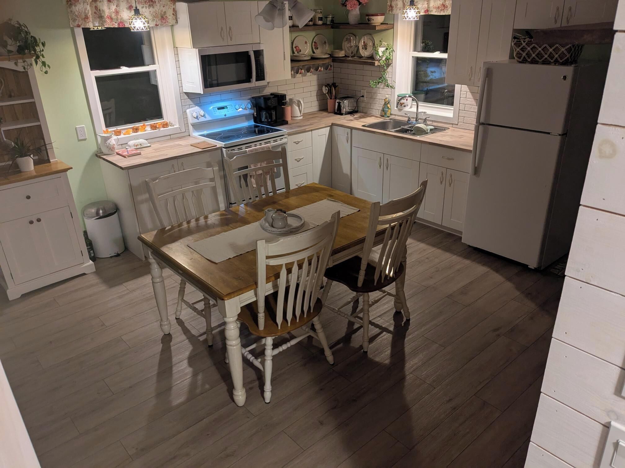 A kitchen with white cabinets, a wooden dining table, and a built-in oven.