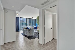 A modern interior with a hallway leading to a living area with a sofa and a coffee table. - X Lounge IX Signature | 3 BR/3 Ensuite Residence (Miami)