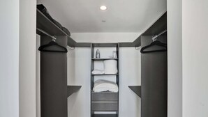 Um closet espaçoso com uma estante central, dois armários com cabideiro de cada lado e uma luminária no teto.