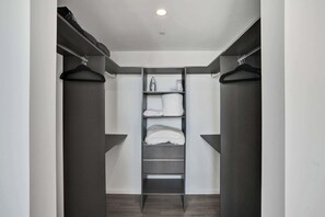 A walk-in closet with a central shelving unit, two hanging closets on either side, and a ceiling light. - X Lounge IX Signature | 3 BR/3 Ensuite Residence (Miami)