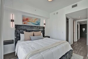 Ein modernes Schlafzimmer mit einem großen Bett, einem Kopfteil mit vertikalen Linien und einem Gemälde darüber.