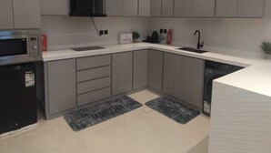 A modern kitchen with grey cabinets, a microwave, a dishwasher, and a sink. - OrbitNet - A05 (Madina)