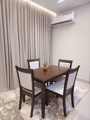 Un coin repas avec une table et des chaises, un climatiseur fixé au mur et un rideau.