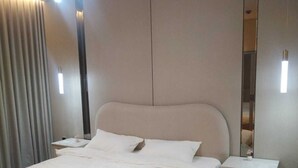 A hotel room with a large bed, bedside tables, a mirror, and a light fixture. - OrbitNet - A05 (Madina)