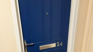 Eine blaue Tür mit Briefschlitz aus Metall und einer Nummernschild mit der Adresse 24.