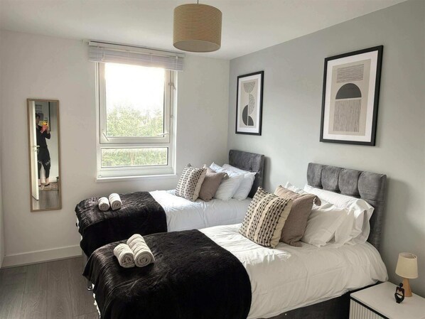A bedroom with two beds, a window, and framed artwork on the wall.