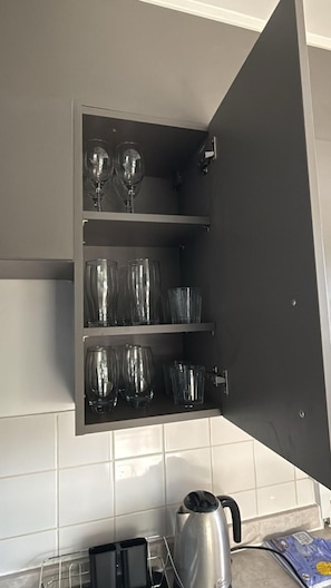A kitchen with a built-in wine rack holding multiple wine glasses and a kettle on the counter.