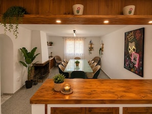 A dining area with a glass table, wooden chairs, and a wooden counter with a candle.