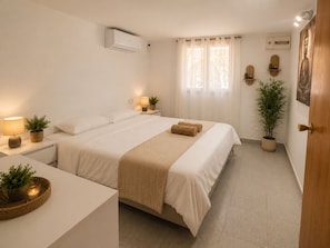A bedroom with a bed, bedside tables, a window with curtains, a wall-mounted air conditioner, and a door.