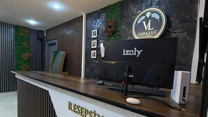 A reception desk with a modern design, featuring a logo, a brand name, and a computer setup. - Vera Luz Arsuz (Arsuz)