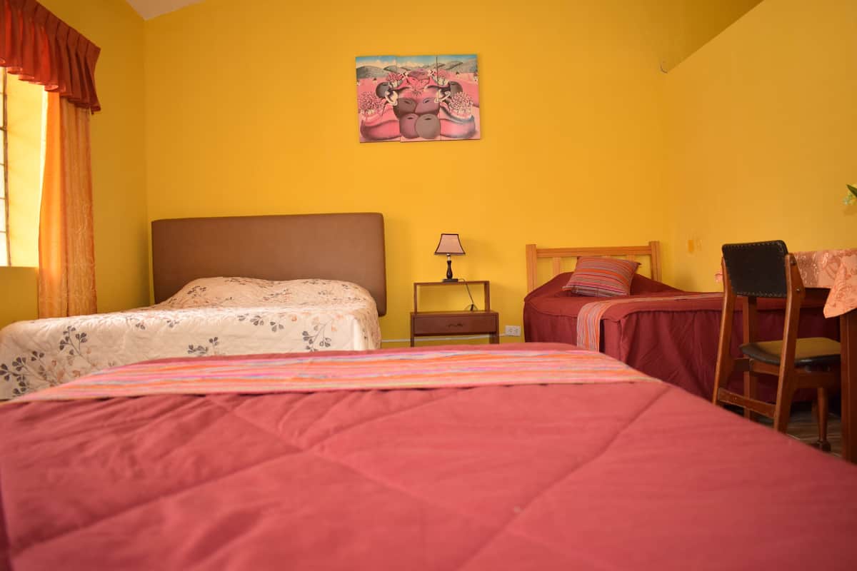 A bedroom with two beds, a nightstand, a chair, and a painting on the wall.