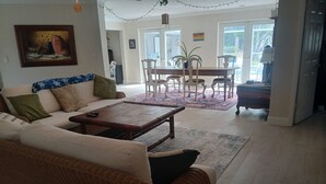Een woonkamer met een bank, salontafel en een eethoek met stoelen en een tafel.