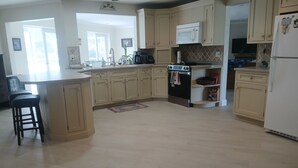 Een keuken met lichte houten kastjes, een centraal eiland, een magnetron, een fornuis en een koelkast.