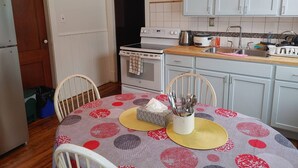 Une cuisine avec une table à manger, des meubles blancs, une cuisinière et un évier.