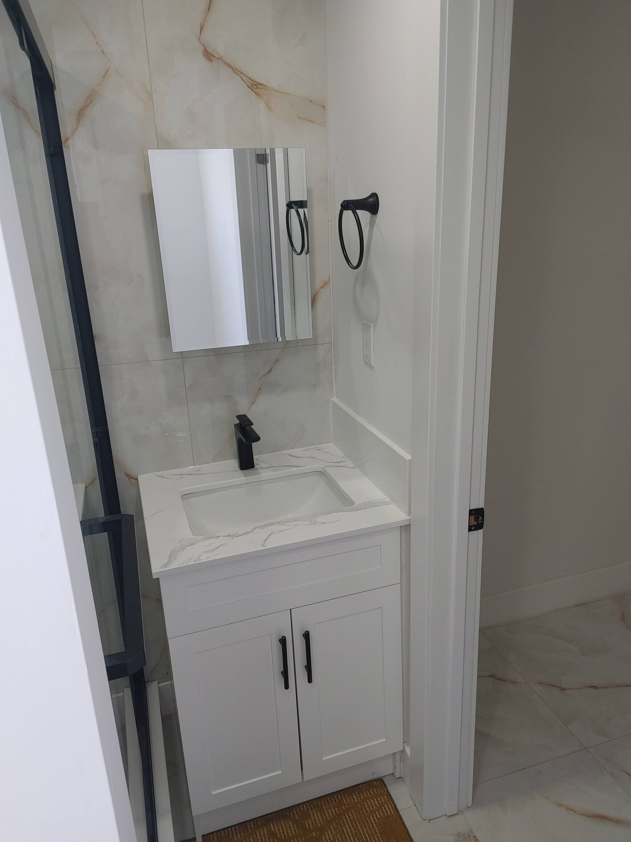 A bathroom with a white sink, mirror, and cabinets.