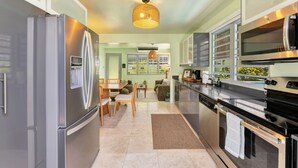 A modern kitchen with stainless steel appliances, a dining area with a table and chairs, and a large window with a view. - 4BR Pool Home | 5 Min to Beach, San Juan (San Juan)
