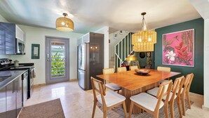 A modern kitchen with a dining area, stainless steel appliances, and a large wooden table. - 4BR Pool Home | 5 Min to Beach, San Juan (San Juan)