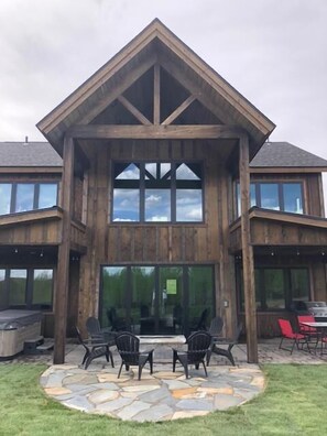 Ein zweistöckiges Holzhaus mit einer Terrasse und Gartenmöbeln.