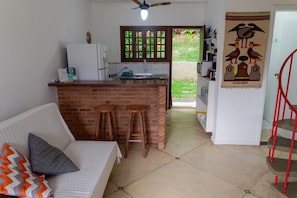 Eine Küche mit Kochinsel aus Backstein, einem weißen Kühlschrank und Holzstühlen.