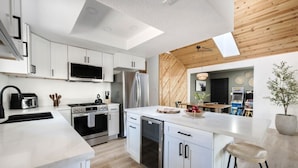 A modern kitchen with white cabinetry, stainless steel appliances, and a wooden ceiling. - Maverick`s Cabin - HotTub, GameRm, Firepit, fenced (Big Bear)